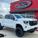 White 2023 GMC Sierra 1500 with 6” Rough Country Lift on 22x12 Axe Design Icarus Wheels in Satin Black & 35x12.50R22 Nitto Recon Grappler Tires White 2023 GMC Sierra 1500 with 6” Rough Country Lift on 22x12 Axe Design Icarus Wheels in Satin Black & 35x12.50R22 Nitto Recon Grappler Tires